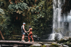 A couple stands in front of a waterfall on Hike & Seek 12 Apostles, Otways & Great Ocean Road day tour