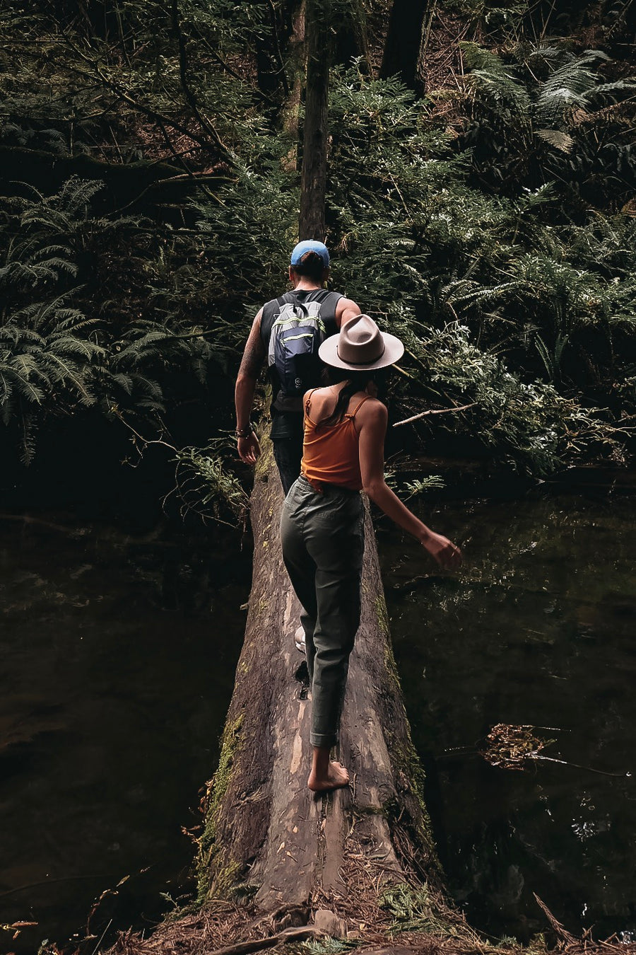 Couple walks across a log over a creek on Hike & Seek day tour from Melbourne