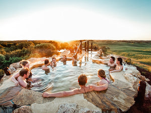 Group of friends soak on hot pools at Peninsula Hot Springs during Hike & Seek tour